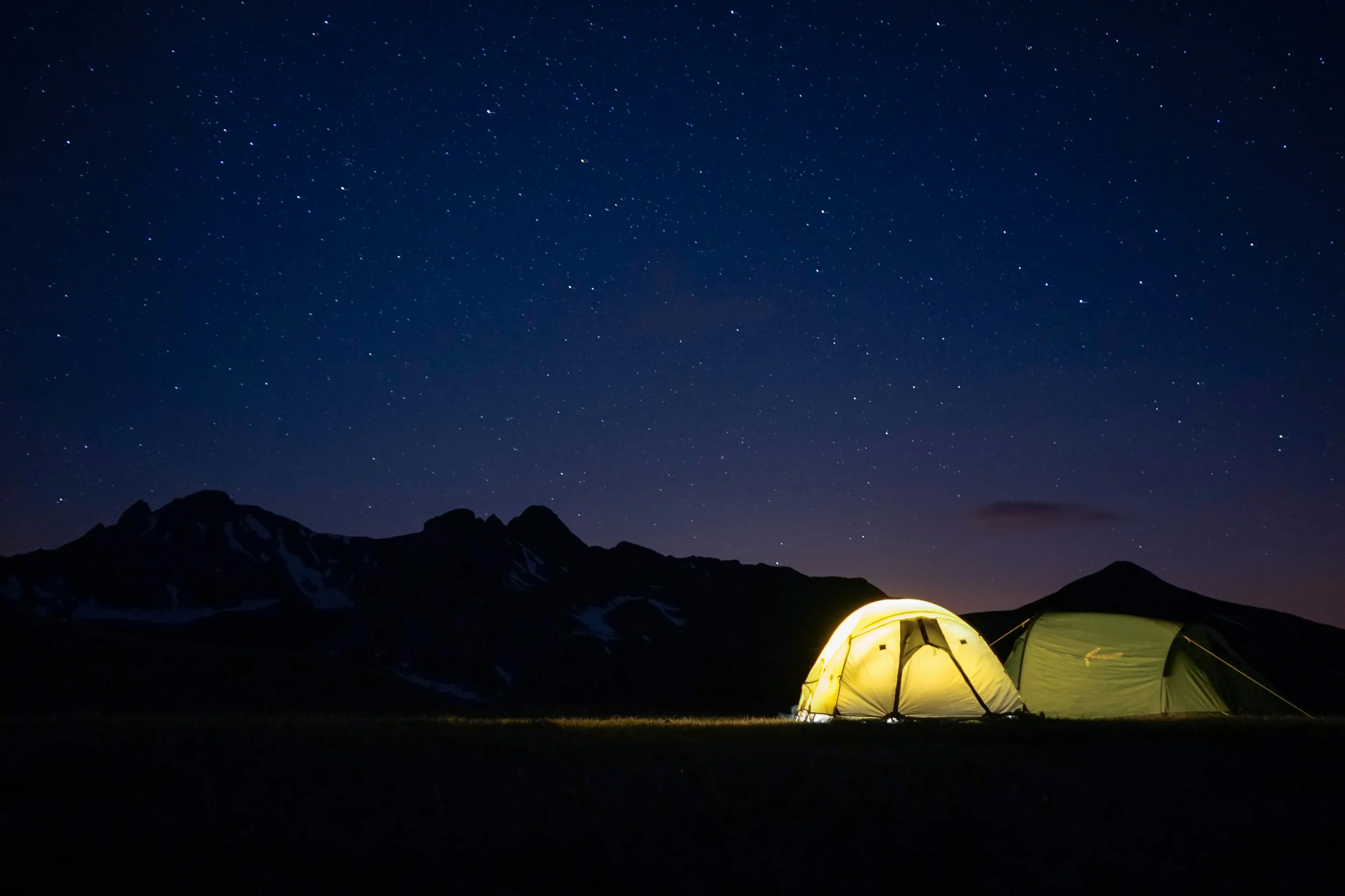 Single tent under a vast starry alpine sky