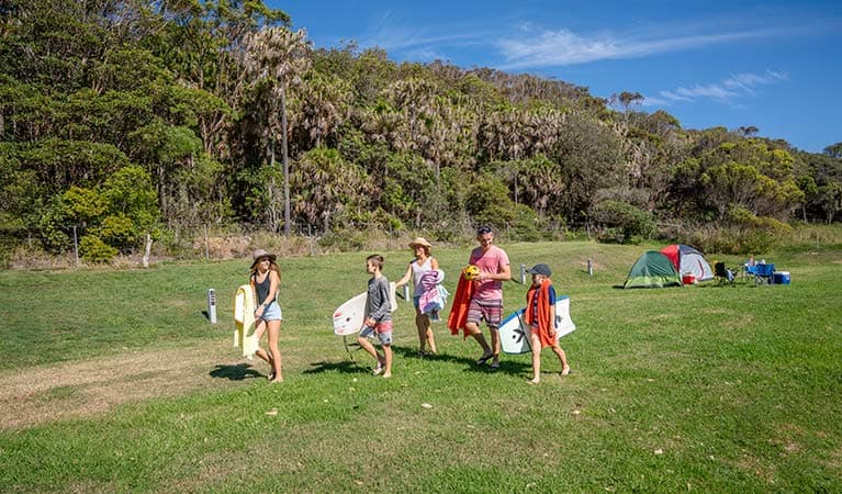 A family walks from their tents to the beach, at The Ruins campground in Booti Booti National Park. Photo credit: John Spencer © DPIE