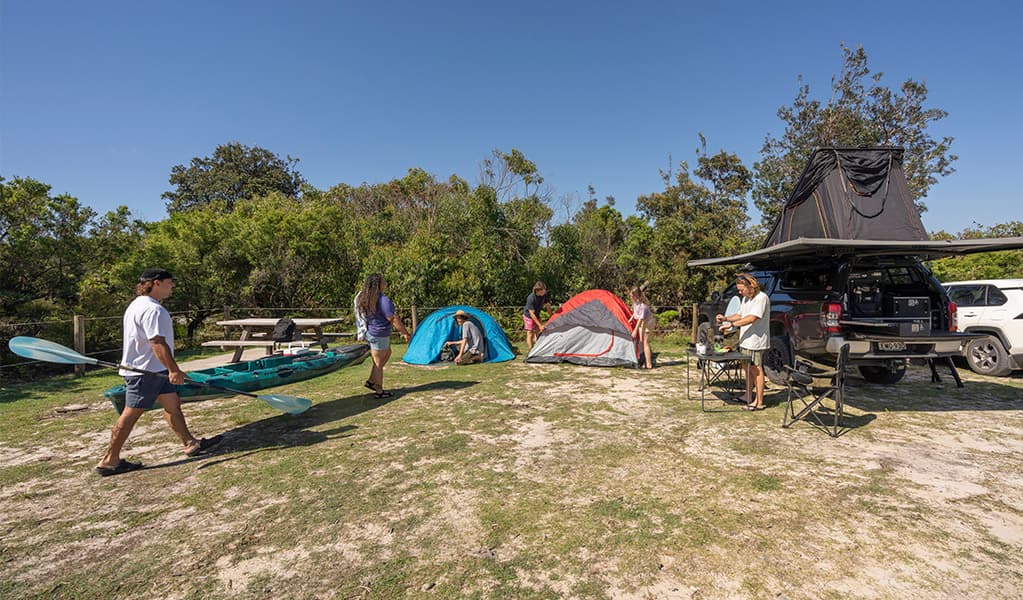 Campers heading off with their kayak at Mibanbah-Black Rocks campground. Credit: John Spencer © DCCEEW