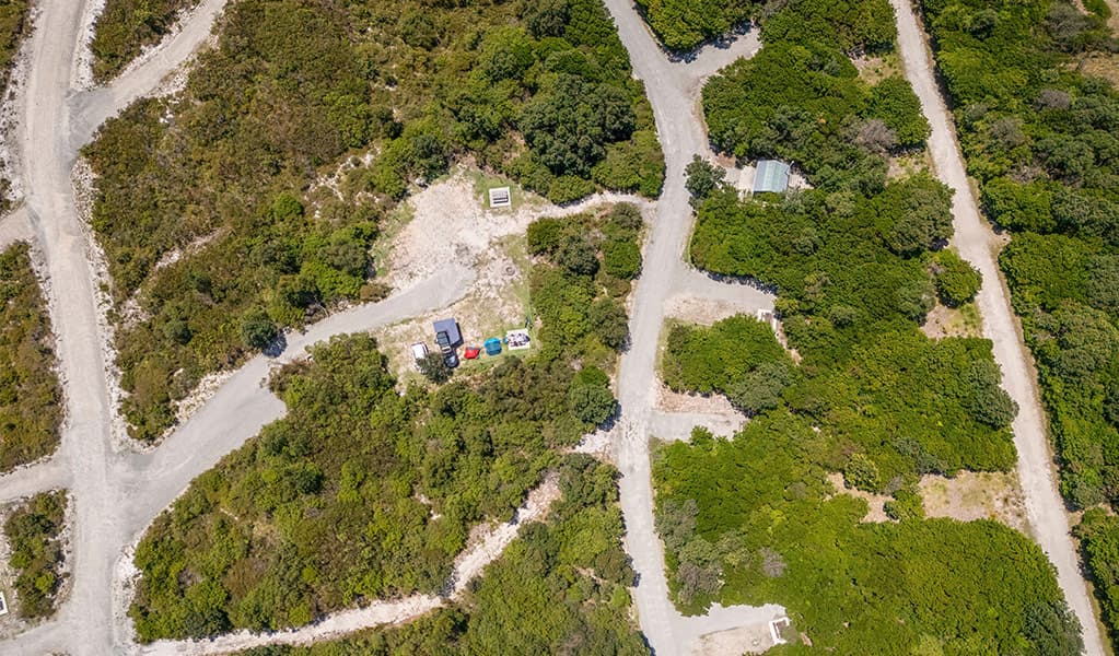 Aerial view of campsites, bushland and the access road at Mibanbah-Black Rocks campground. Credit: John Spencer © DCCEEW