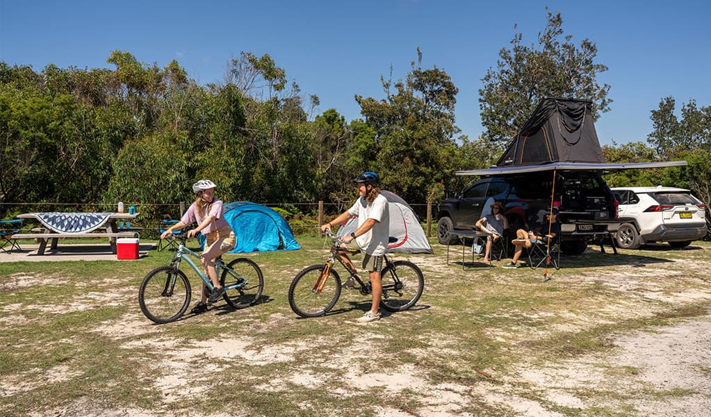 Campers heading off on their bikes at Mibanbah-Black Rocks campground. Credit: John Spencer © DCCEEW