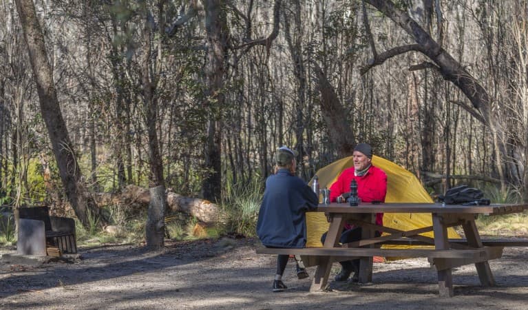 A couple sitting at a picnic table with their tent in the background at Barokee campground in Cathedral Rock National Park. Photo: Josh Smith © DPE