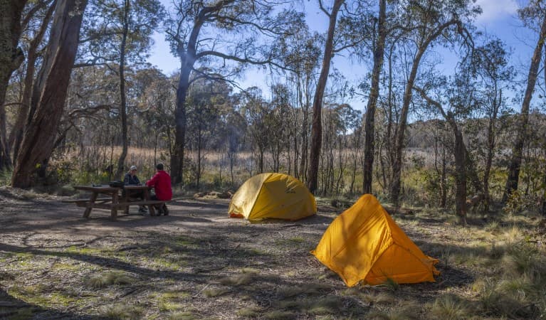 Two people sit at a picnic table with their tents in the foreground at Barokee campground, Cathedral Rock National Park. Photo: Josh Smith © DPE