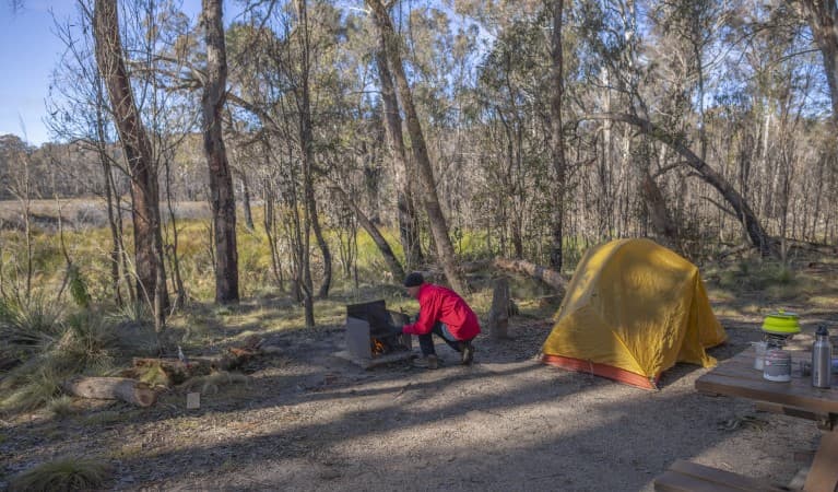 A man tends to the wood barbecue next to his tent at Barokee campground in Cathedral Rock National Park. Photo: Josh Smith © DPE
