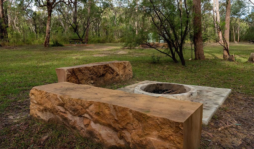 Sandstone seating blocks and fire pit at Ten Mile Hollow campground. Photo: Allan Chawner © DCCEEW