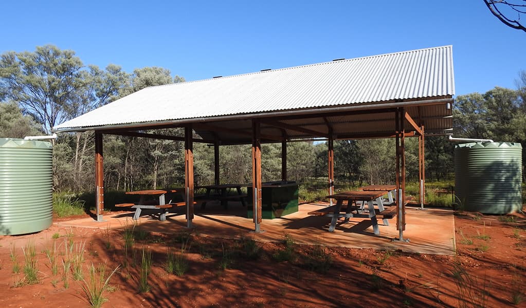 Photo of picnic tables and a barbecue under a shelter at Dry Tank campground and picnic area at Gundabooka National Park. Photo credit: Jess Ellis/DPE © DPE