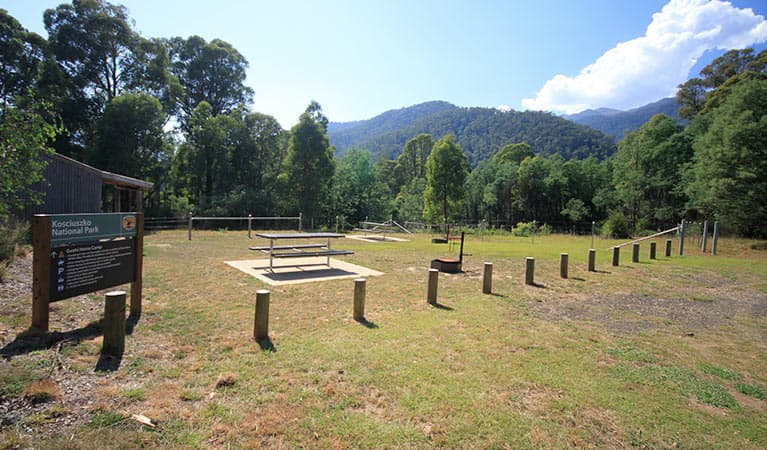 Sign and facilities at Geehi horse camp, with views of forested mountains in Kosciuszko National Park. Photo: Elinor Sheargold © DPIE