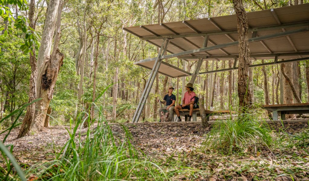2 campers sitting under the picnic shelter at Oaky Beach campground. Credit: John Spencer © DPE