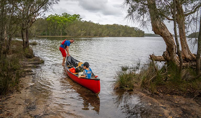 2 people in a canoe on Boolambayte Lake at Violet Hill campground in Myall Lakes National Park. Photo: John Spencer © DPIE