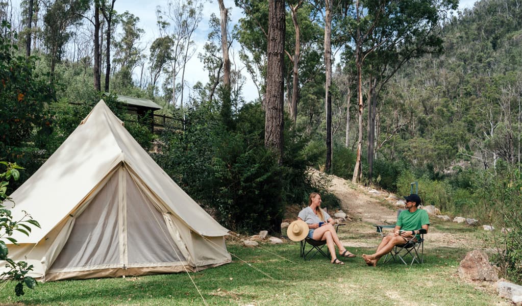 People sitting by their tent at The Junction campground, Nymboi-Binderay National Park. Photo: Jay Black © DCCEEW