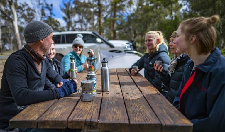 A group of friends sitting at a picnic table at Dangars Gorge campground in Oxley Wild Rivers National Park. Photo: John Smith © DPE