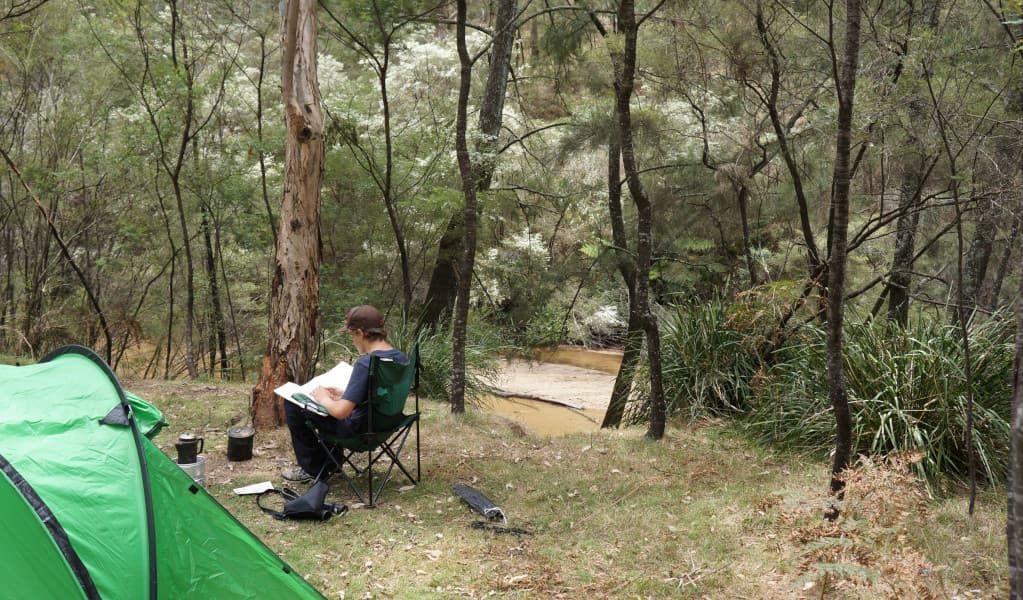 Camper relaxing by the river Newnes campground. Credit: Stephen Alton © DPE