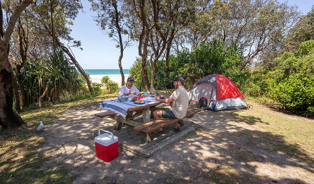 Campers enjoying lunch on the picnic bench on their campsite, Ilaroo campground. Credit: John Spencer © DCCEEW